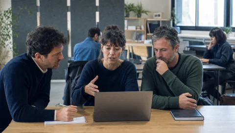 Équipe de consultants réunie autour d’un ordinateur dans un espace de travail partagé